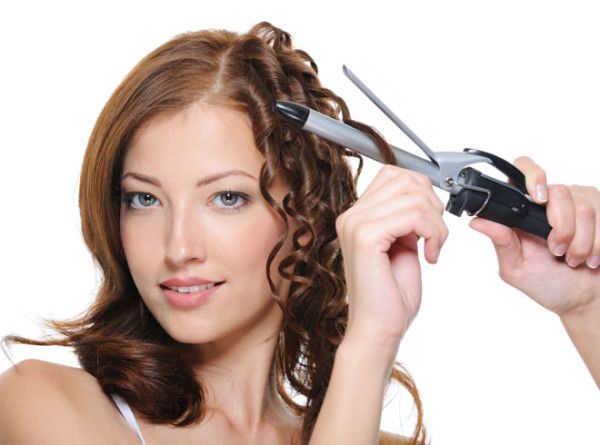 девушка крутит волосы на плойку