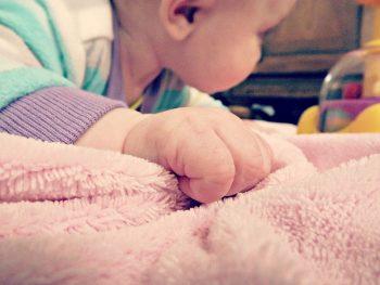 грудничок держится за полотенце